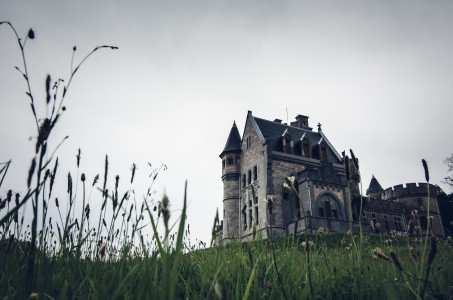 A low angle shot of an old beautiful castle on a grassy hill